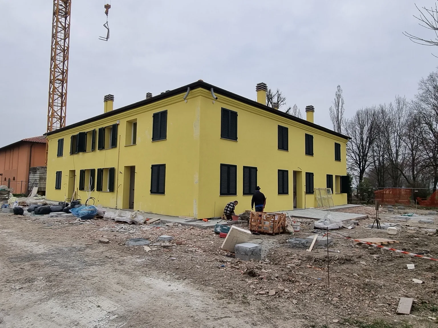 Vista angolare dell’edificio residenziale durante il completamento dei serramenti e delle persiane.