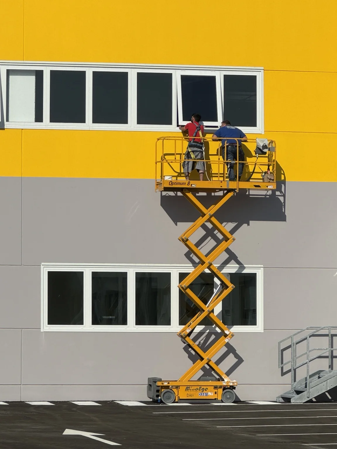 Regolazione dei serramenti in quota sulla facciata gialla del polo DHL Express.