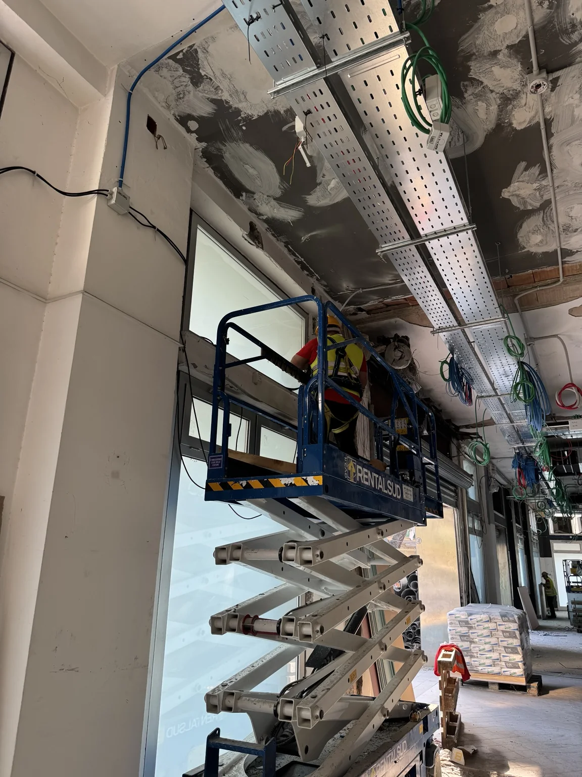 Operatore su piattaforma durante la posa dei serramenti nel Supermercato DPiù di Foggia.